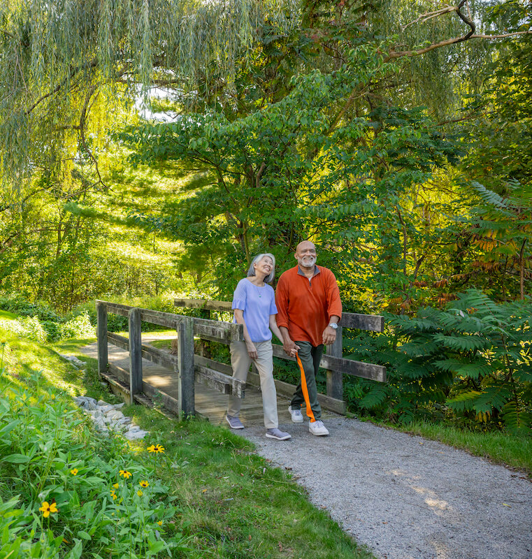 Senior couple holding hands while walking across a bridge